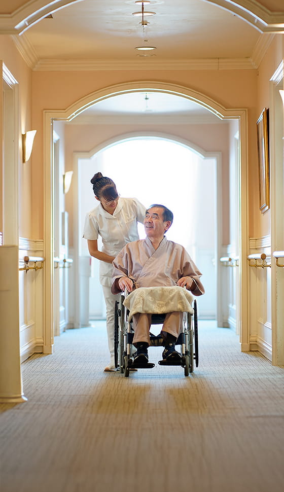 車椅子に乗った男性が看護師と話をしている様子